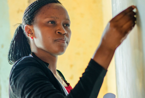 The photo shows a woman writing on a chalkboard